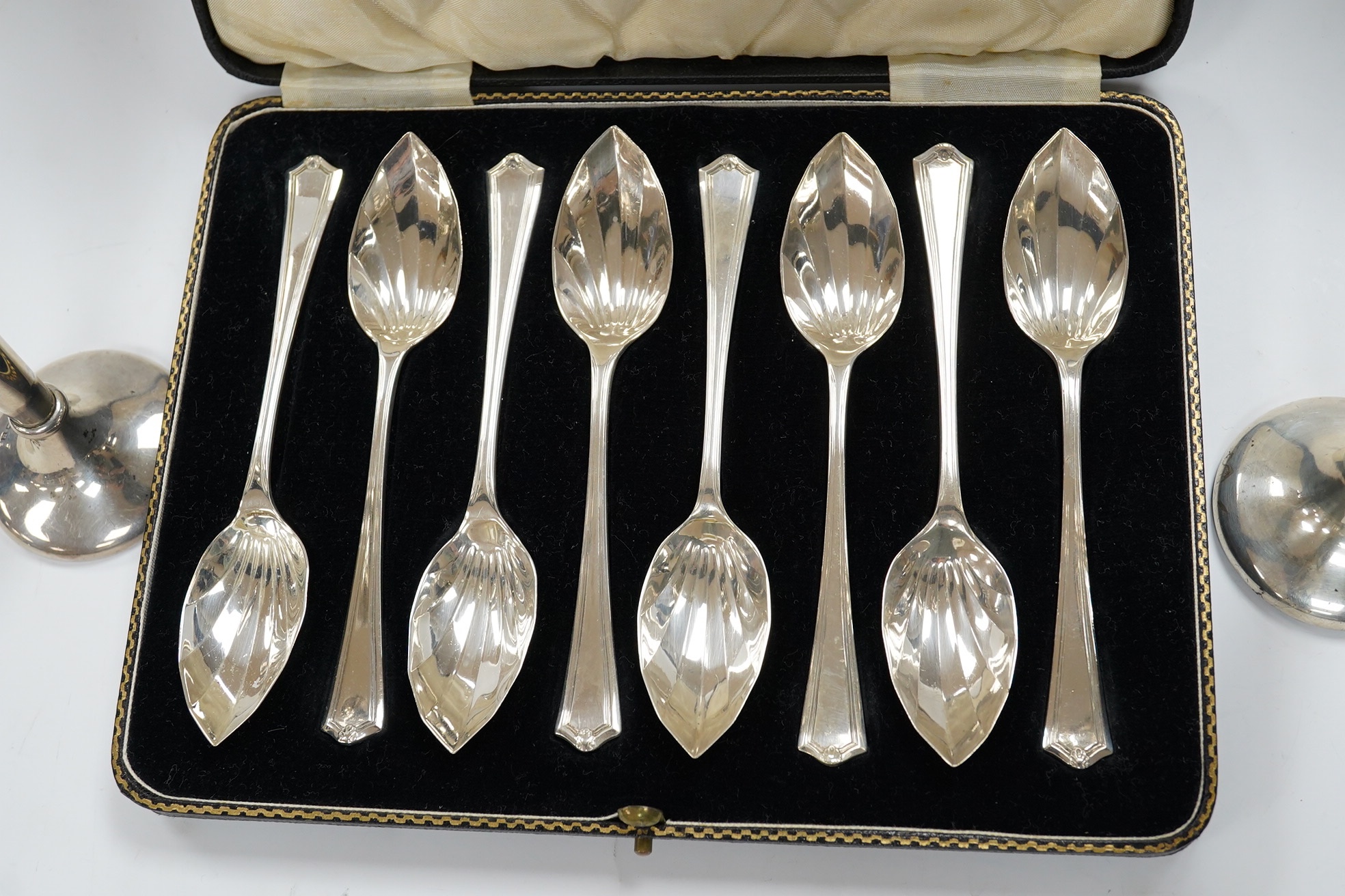 A cased set of eight George V silver grapefruit spoons, Sheffield, 1933 and a pair of silver spill vases, 17.5cm. Condition - poor to fair